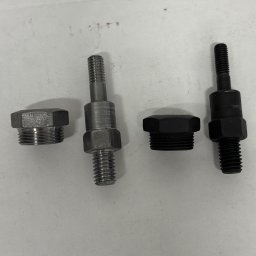 MAGMA Tech - Dwa komplety śrub i nakrętek, jeden srebrny, drugi czarny, leżące na jasnym tle. Widoczne gwinty i sześciokątne nakrętki.