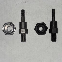 MAGMA Tech - Dwa zestawy metalowych elementów: srebrna nakrętka i śruba z gwintem oraz czarna nakrętka i śruba z gwintem, leżące na szarym tle. Precyzyjna obróbka.