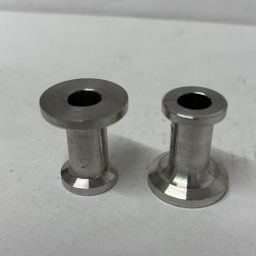 MAGMA Tech - Dwa identyczne, metalowe elementy z otworem, prawdopodobnie wykonane na tokarce, leżące na białym tle. Widoczne ślady obróbki.