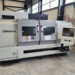 New Energy Transfer Sp. z o.o. - Szara tokarka CNC marki Wagner z panelem sterowania i zamkniętą przestrzenią roboczą, widoczna w hali produkcyjnej z oknami i metalową konstrukcją dachu.