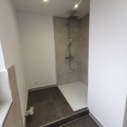 K1 - REMONTY & DOCIEPLENIA PRZEMYSŁAW KULKA - Nowoczesna kabina prysznicowa walk-in z szarymi płytkami i ciemną podłogą. Minimalistyczny design, oświetlenie punktowe. Widok na brodzik i baterię.