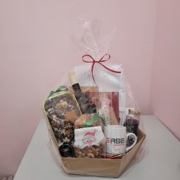 MALINOWE SMAKI EMILIA WIECZOREK - Świąteczny kosz prezentowy ze słodkościami, winem i kawą, zapakowany w celofan z czerwoną kokardą. Idealny upominek ze Świdnicy na Boże Narodzenie.