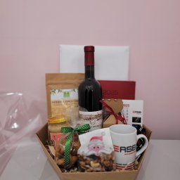 MALINOWE SMAKI EMILIA WIECZOREK - Kosz prezentowy z winem, herbatą, miodem, orzechami w świątecznym opakowaniu i kubkiem z logo firmy, na jasnym tle. Idealny upominek firmowy.