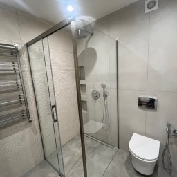 Yevhen Zatula - Nowoczesna łazienka z kabiną prysznicową typu walk-in, grzejnikiem drabinkowym i podwieszaną toaletą. Minimalistyczny design, szare płytki z subtelną fakturą.