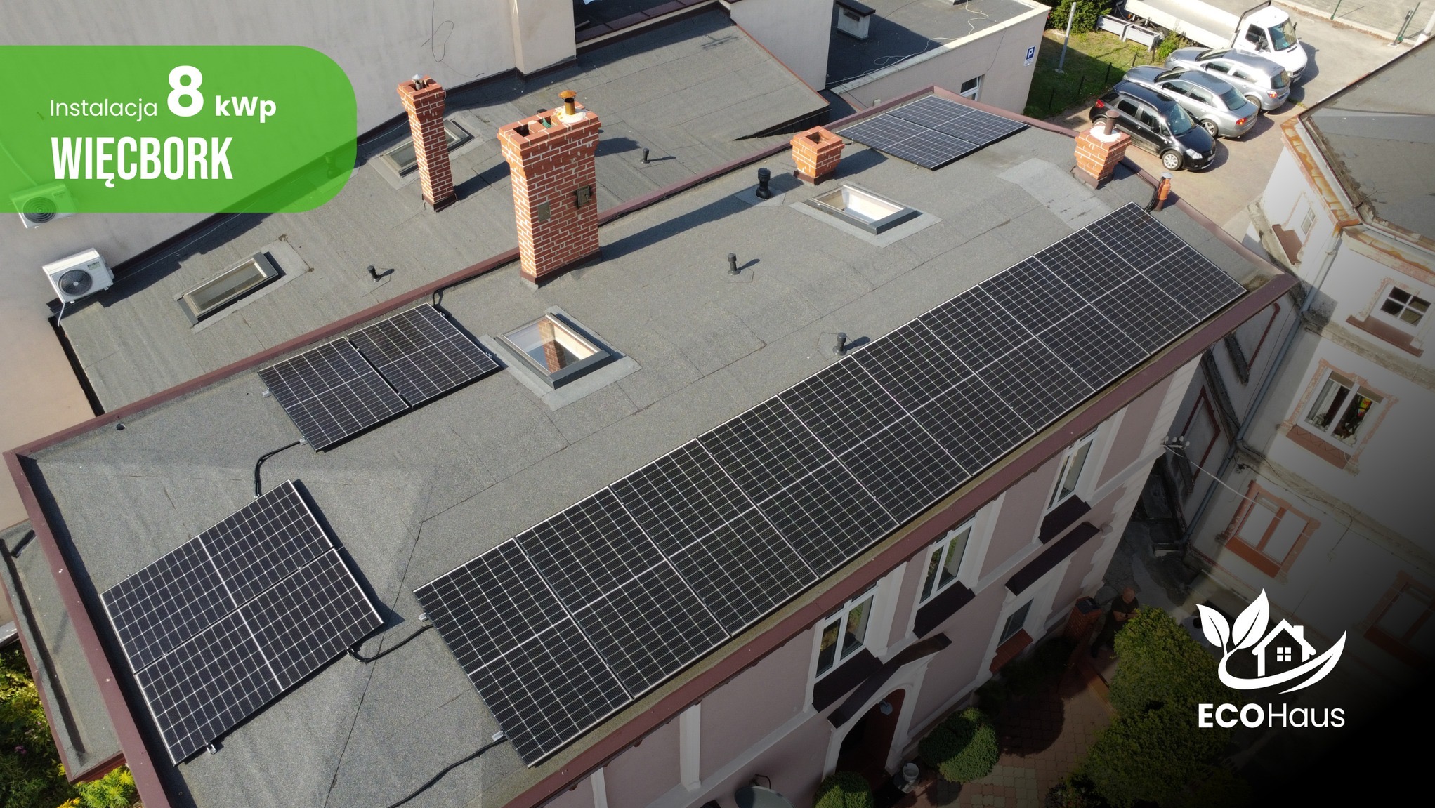 Instalacja fotowoltaiczna 8 kWp na dachu budynku w Więcborku. Widok z góry na panele słoneczne, kominy, okna dachowe i logo EcoHaus w prawym dolnym rogu.