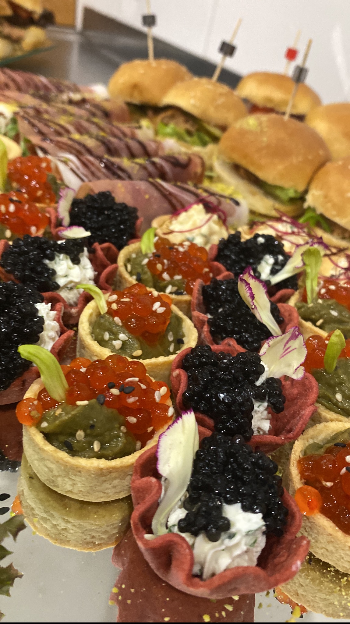 Eleganckie przekąski cateringowe: mini tartaletki z kawiorem i pastą, kanapki z szynką i sałatą, ułożone na srebrnej tacy. Idealne na wykwintne przyjęcie.