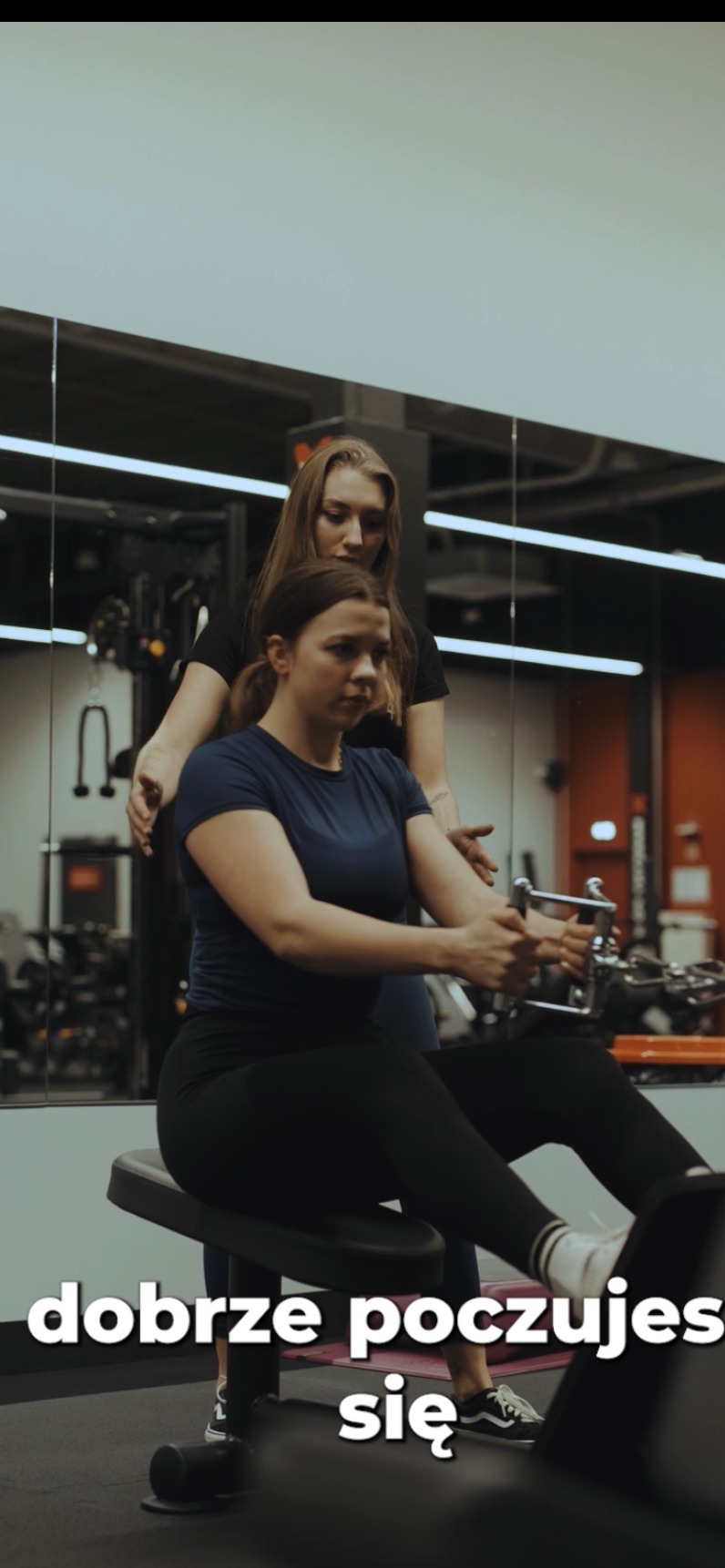 Kobieta ćwiczy na maszynie pod okiem instruktorki w siłowni w Bielsku-Białej. Trening na wzmocnienie mięśni pleców, profesjonalne wsparcie i motywacja.