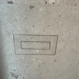 Szary gres z odpływem liniowym w podłodze. Minimalistyczny design, precyzyjne ułożenie płytek, nowoczesne wykończenie łazienki. Detal odpływu.