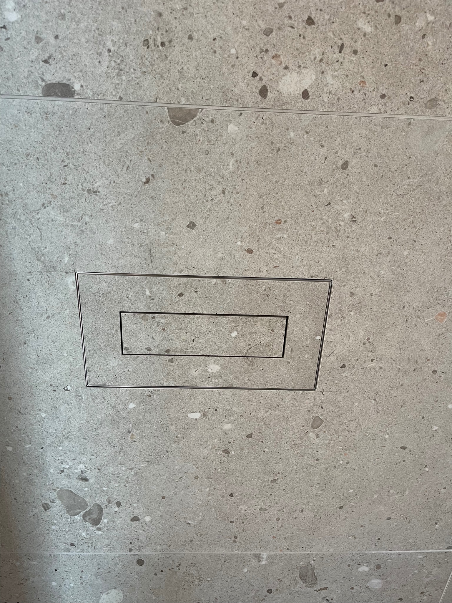 Szary gres z odpływem liniowym w podłodze. Minimalistyczny design, precyzyjne ułożenie płytek, nowoczesne wykończenie łazienki. Detal odpływu.