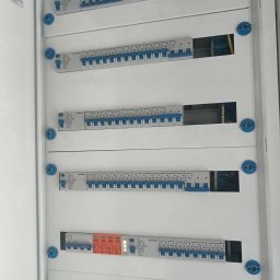 SolidVolt - Rozdzielnica elektryczna z bezpiecznikami i przewodami, widoczne elementy instalacji, zabezpieczenia i okablowanie wewnątrz szafki.