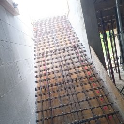 ESSENTIS Konrad Joński - Siatka zbrojeniowa na deskowaniu, widok z góry. Elementy konstrukcyjne z betonu komórkowego w tle. Różowe znaczniki na zbrojeniu.