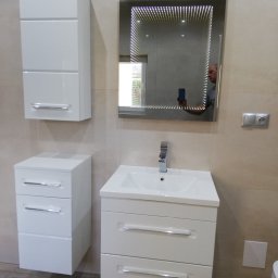 USŁUGI BUDOWLANE ADRIAN KONTOWSKI - Biała szafka łazienkowa z umywalką i lustrem z efektem nieskończoności, odbicie osoby robiącej zdjęcie. Beżowe płytki na ścianach i drewnopodobna podłoga.