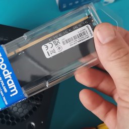 Naprawa Komputerów i Laptopów Serwis Pogotowie Rafał jarosz - Pamięć RAM Goodram DDR4 16GB w przezroczystym opakowaniu, trzymana w dłoni nad czarną obudową komputera. Widoczna etykieta z informacjami technicznymi.