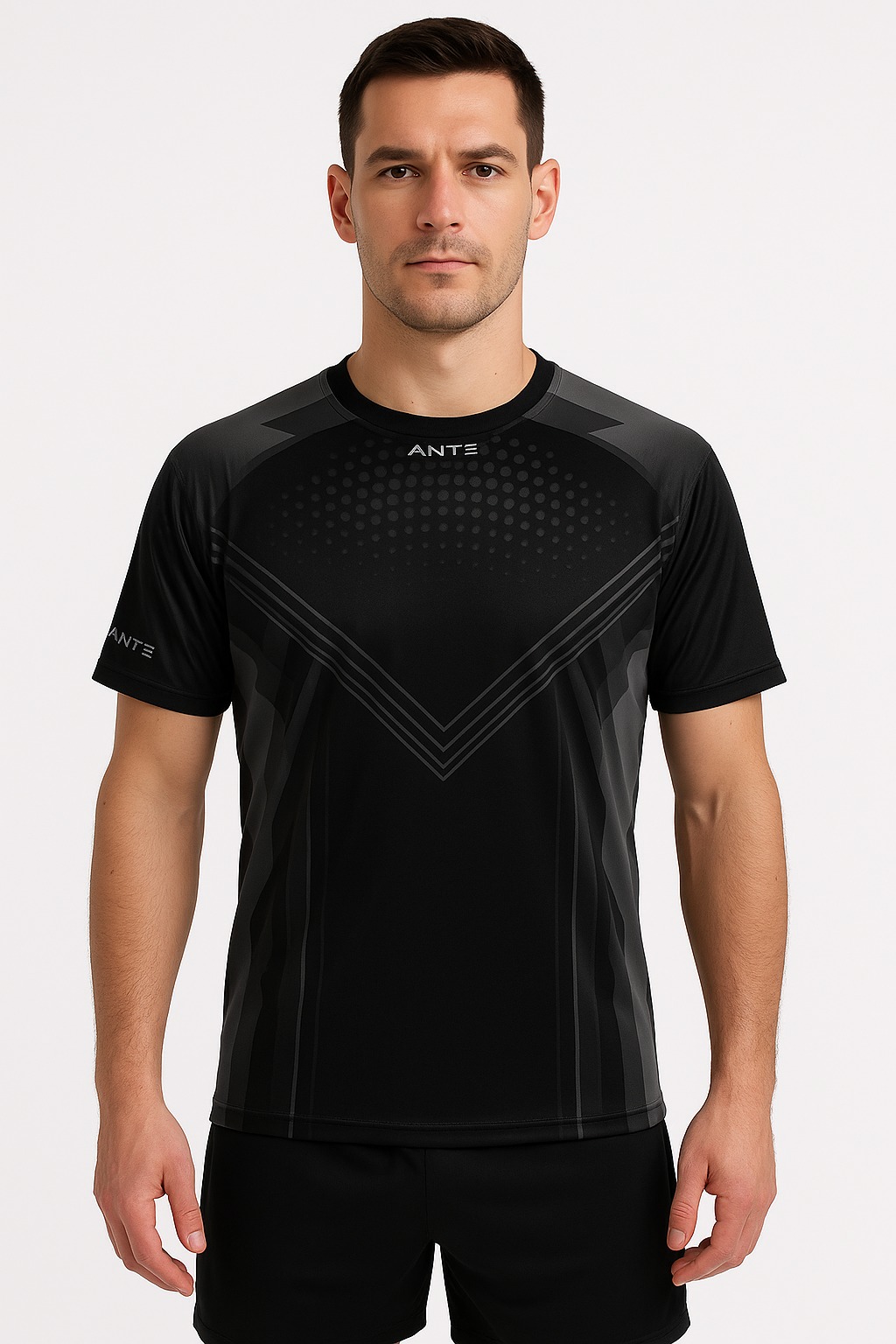Mężczyzna prezentuje czarną, sportową koszulkę z szarymi geometrycznymi wzorami i napisem 'ANTE' na tle białego studia. Krótki rękaw, dopasowany krój.