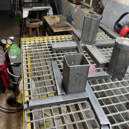 Mobilne Usługi Spawalnicze - Metalowe profile łączone na ruszcie warsztatowym, widoczne narzędzia i butla z gazem. Przygotowanie konstrukcji w warsztacie.