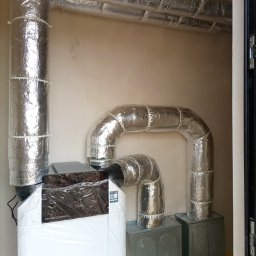 DIAMENT TOMASZ GUZEWSKI - Rekuperator Zehnder ComfoAir Q z izolowanymi przewodami wentylacyjnymi, zamontowany w pomieszczeniu. Widoczne elementy instalacji i podłączenia.