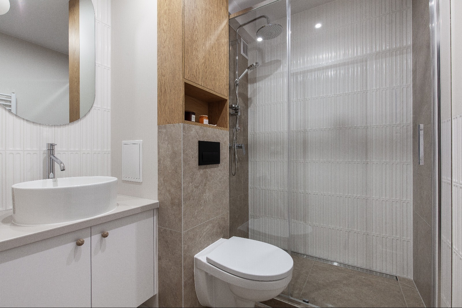 Nowoczesna łazienka z kabiną prysznicową, umywalką nablatową i drewnianą szafką. Białe płytki z subtelnym wzorem i szara ściana tworzą elegancki kontrast.