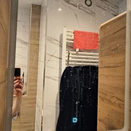 Homedetailingswarzedz - Nowoczesna łazienka z marmurowymi płytkami, widoczna w lustrze z podświetleniem LED. Na grzejniku suszą się ręczniki, a obok umywalka z dozownikiem mydła.