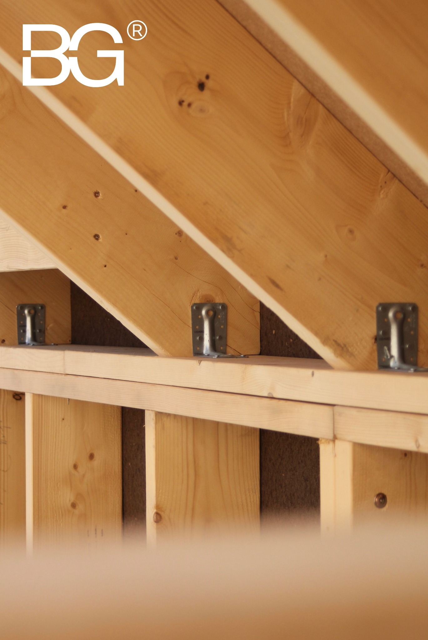 Wnętrze w trakcie budowy: drewniana konstrukcja szkieletowa z widocznymi metalowymi łącznikami i izolacją. Ujęcie z dołu, jasne drewno, surowy stan.