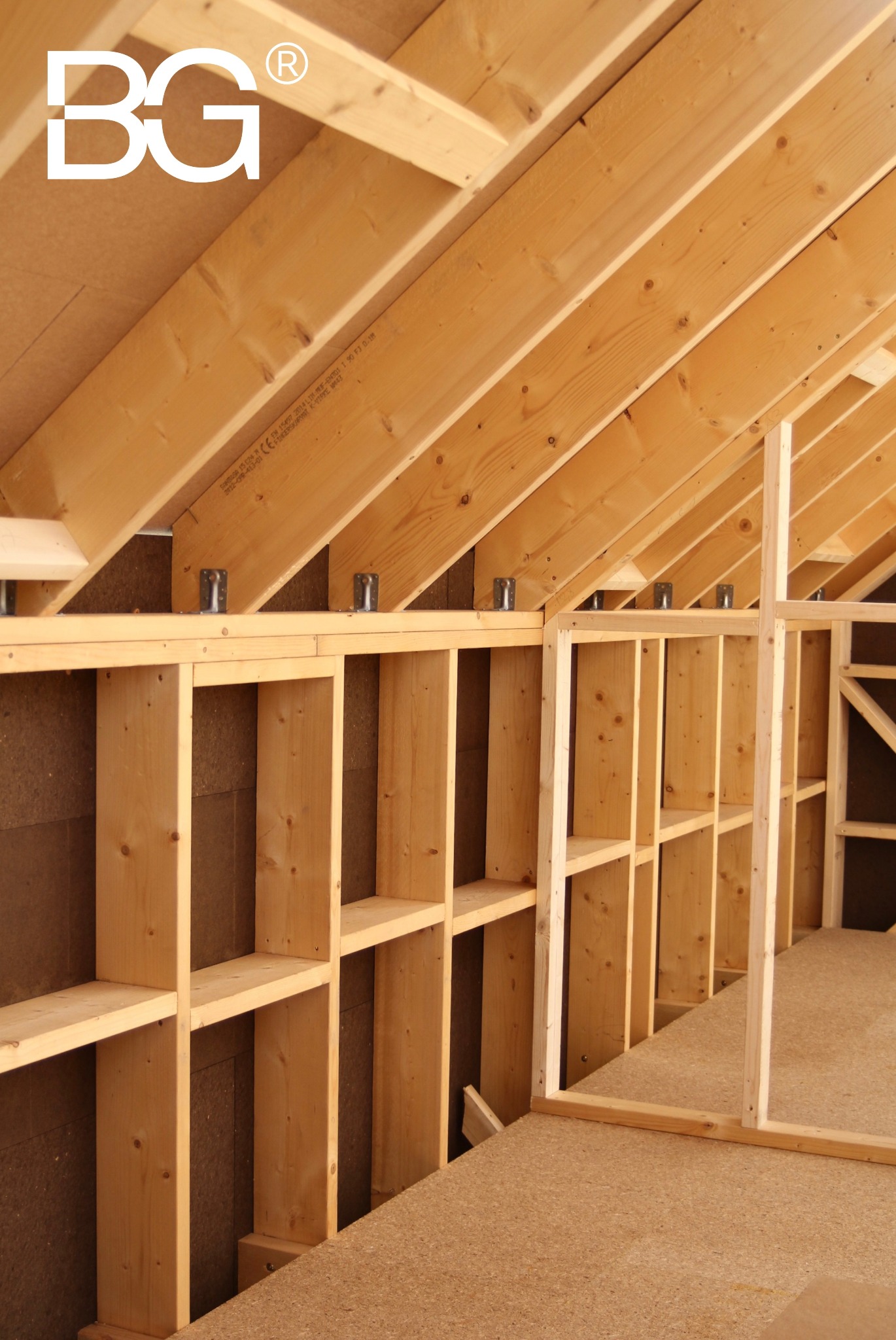 Wnętrze w trakcie budowy: drewniana konstrukcja szkieletowa z widocznymi elementami ścian, stropu i dachu. Surowe drewno, płyty OSB i metalowe łączniki.