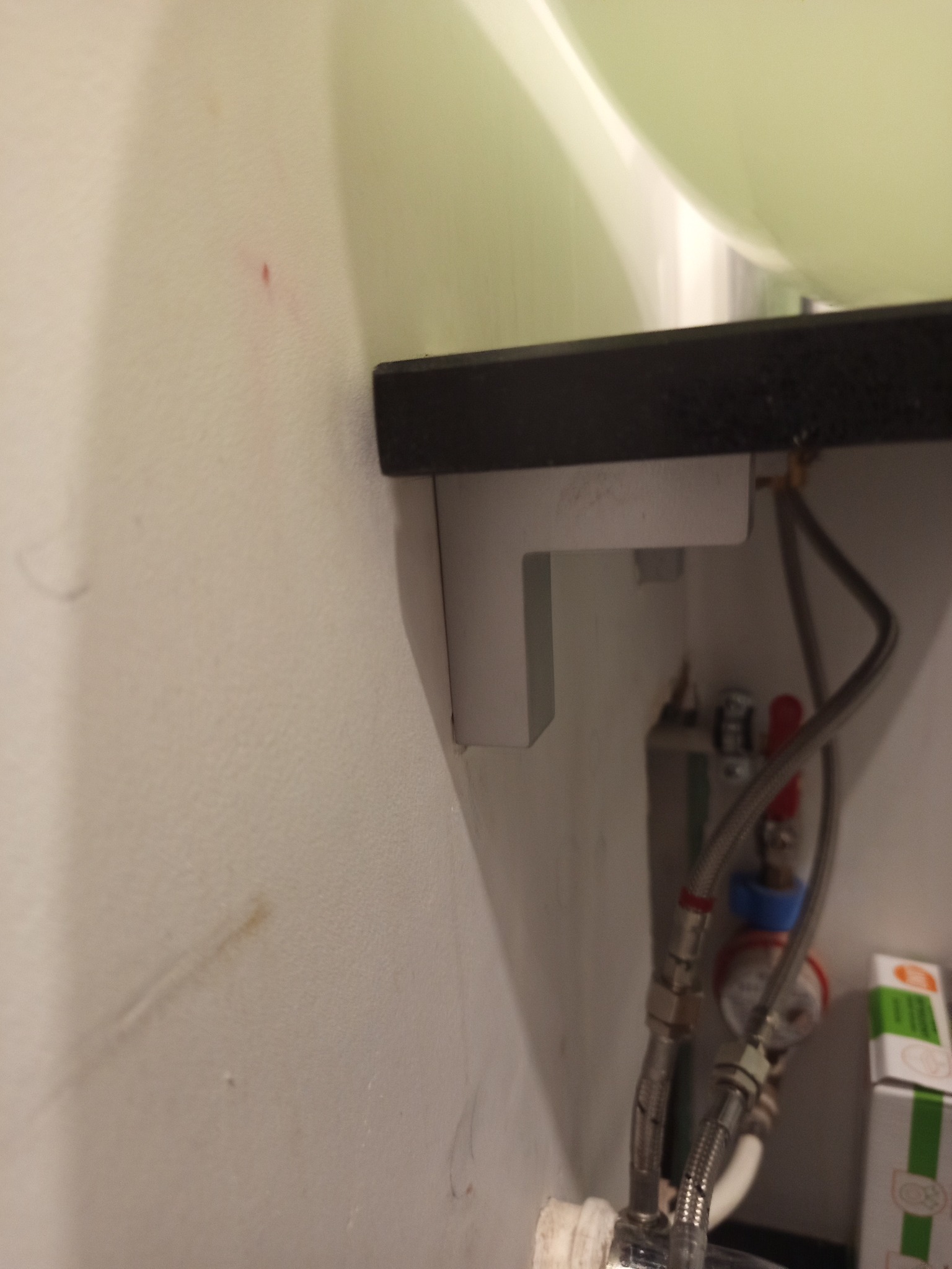 Zamontowany blat umywalki z widocznymi wspornikami i podłączeniem hydraulicznym. Detal montażu z poprawionymi otworami i dłuższymi kołkami.