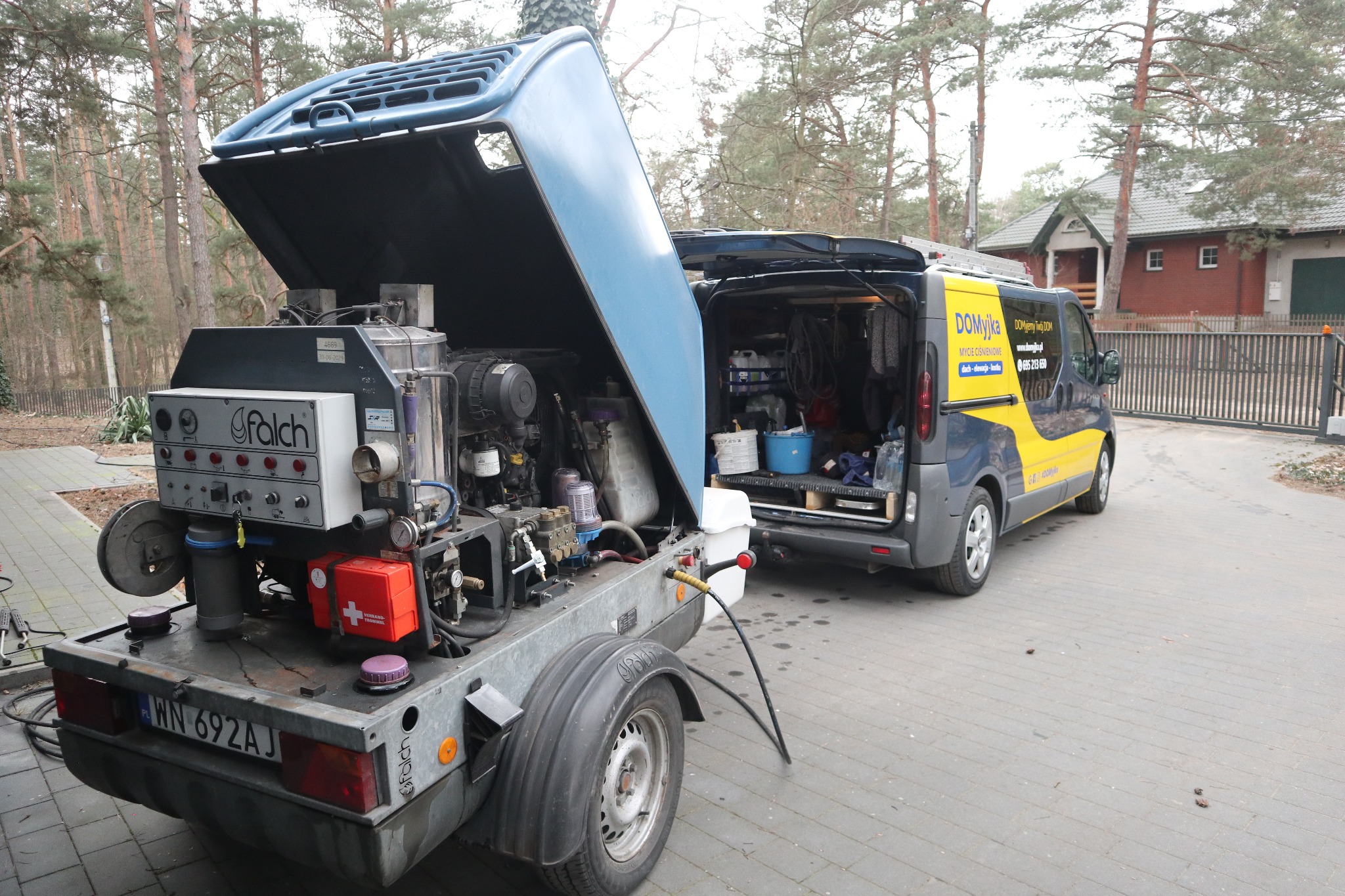 Przyczepa z agregatem ciśnieniowym Falch i bus firmy Domyjka na posesji z kostki brukowej. Sprzęt do czyszczenia dachów i elewacji.