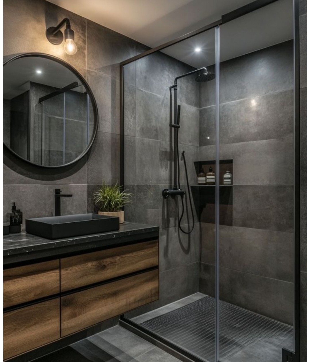Nowoczesna łazienka z kabiną prysznicową typu walk-in, czarną armaturą i drewnianą szafką pod umywalką. Szare płytki imitujące kamień na ścianach.