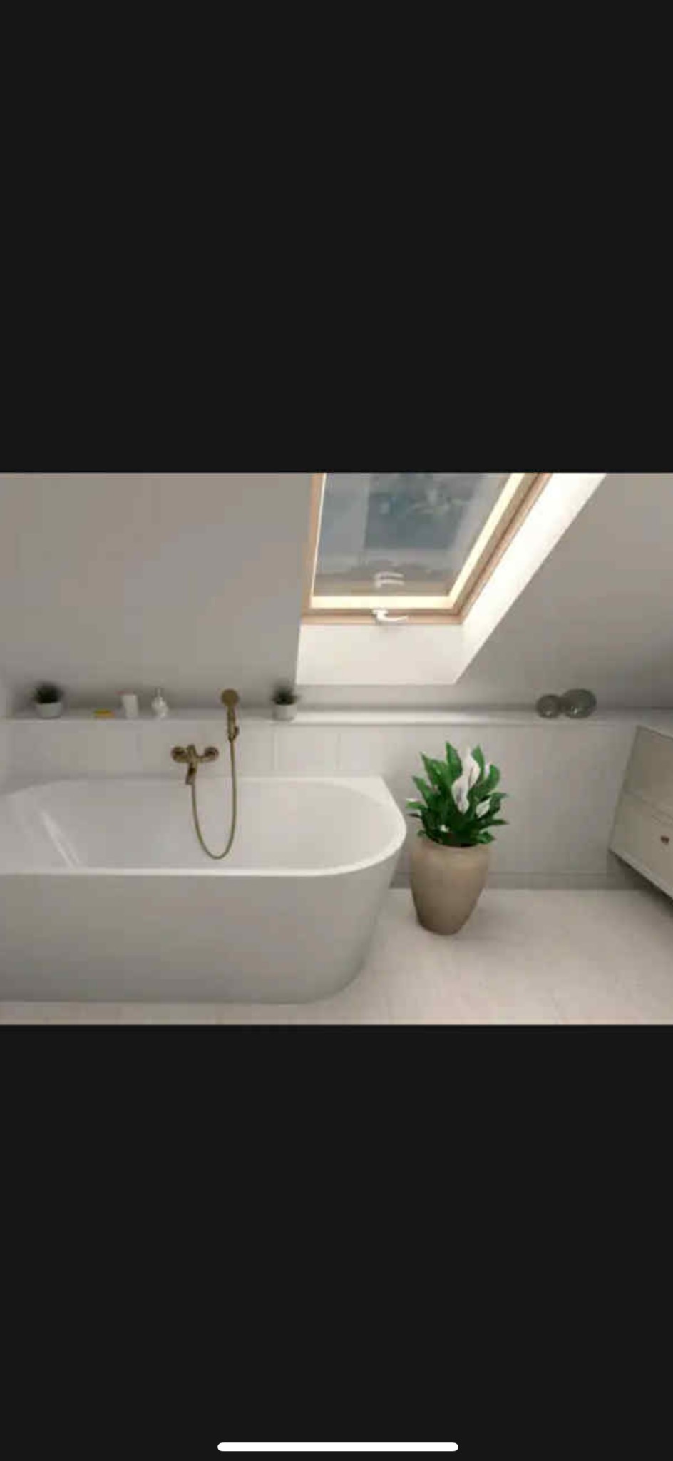 Jasna łazienka na poddaszu z oknem dachowym. Biała wanna wolnostojąca z złotą armaturą, roślina w doniczce. Minimalistyczny design, płytki podłogowe w odcieniach bieli.