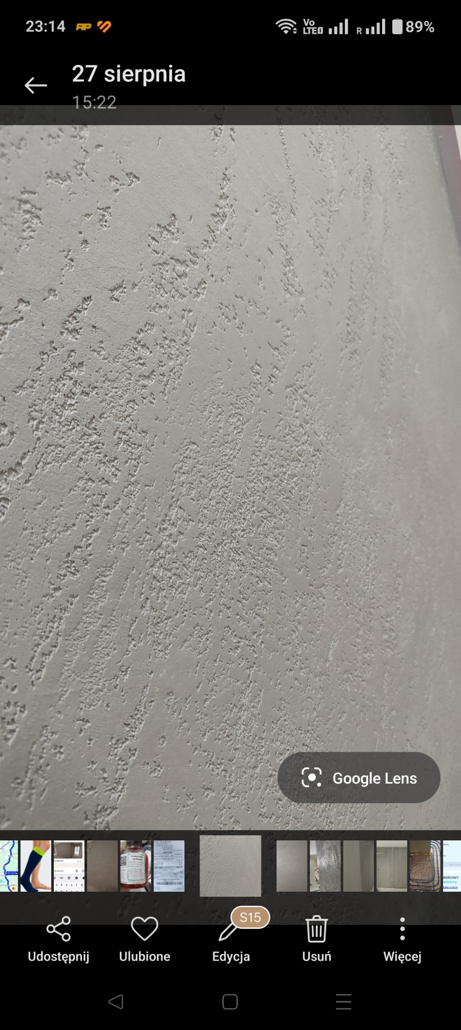 Szara ściana z wyraźną, nieregularną fakturą, wykonana techniką dekoracyjną. Widoczne delikatne cienie podkreślające strukturę. Ujęcie z bliska, ukazujące detale wykończenia.