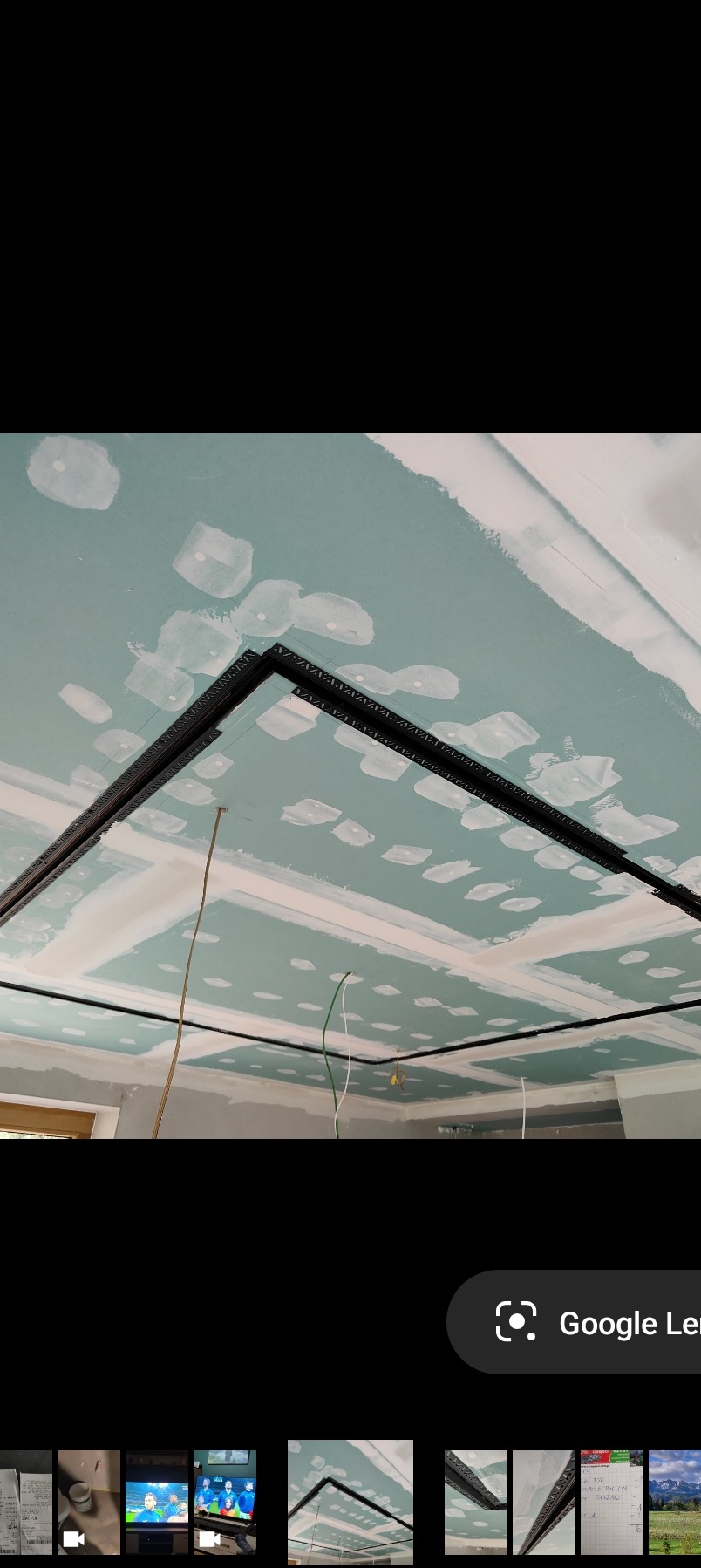 Sufit z płyt karton-gips, wstępnie zagruntowany i z widocznymi łączeniami, z zamontowanymi profilami dekoracyjnymi. Widoczne przewody elektryczne.