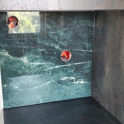 Dominik - Fragment wykończonej kuchni z zielonym marmurem na ścianie i widocznymi puszkami elektrycznymi. Ciemny blat i szara szafka. Nowoczesne wykończenie wnętrza.