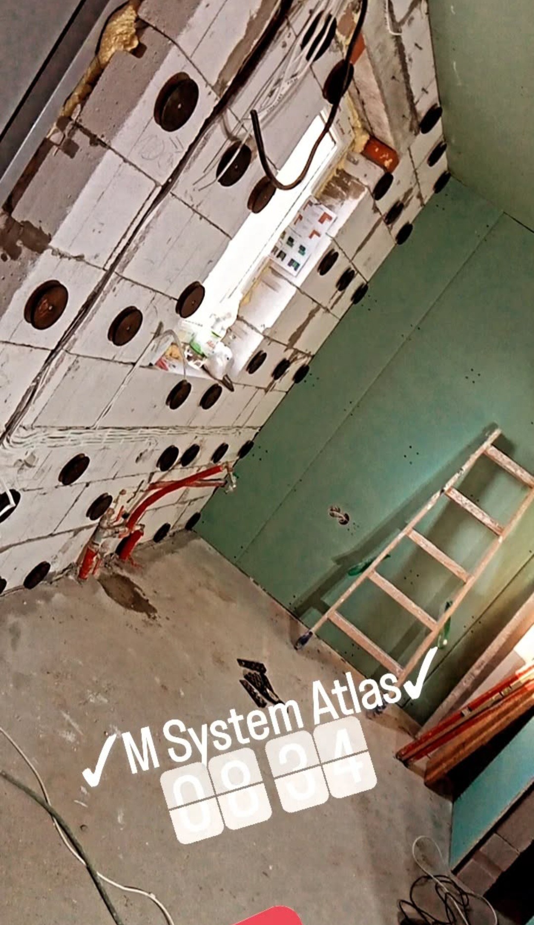 Wnętrze w trakcie prac: ściany z płyt gipsowo-kartonowych, instalacje elektryczne i hydrauliczne, drabina oparta o ścianę. Widoczne elementy montażowe.