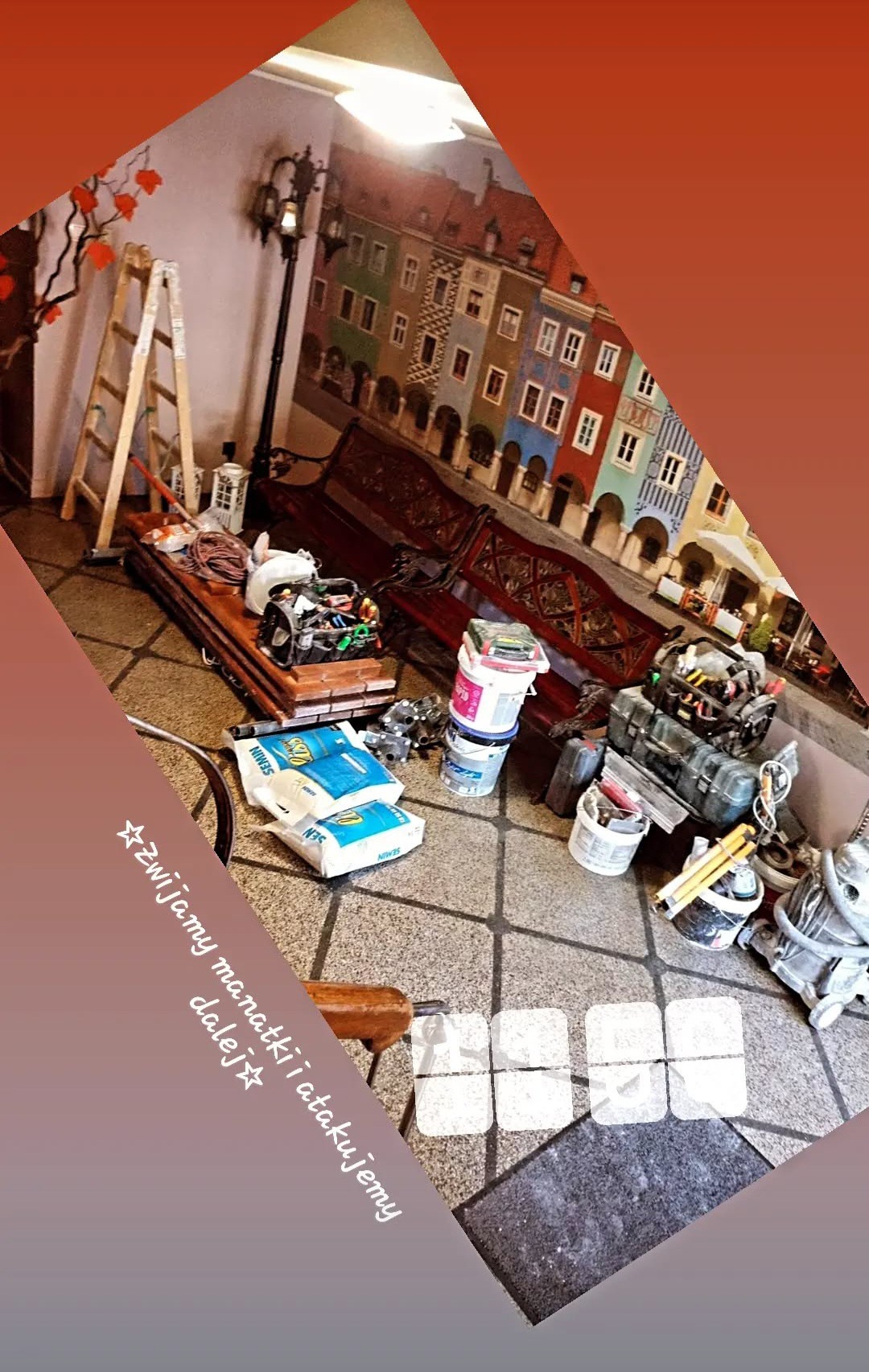 Przygotowania do prac: drabina, narzędzia, worki z gładzią i farby na tle ściany z malowidłem miejskiego krajobrazu. Ukośny kadr.