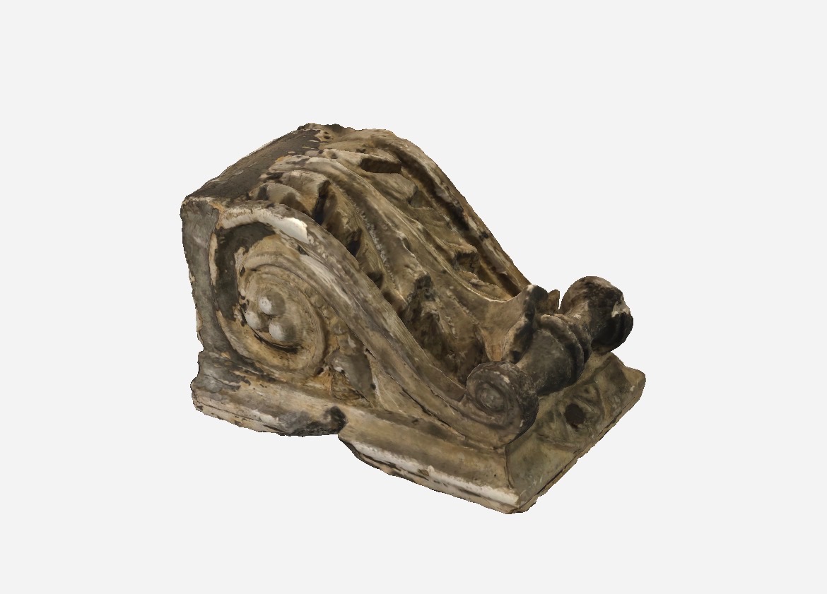 Dekoracyjny, beżowy wspornik z ornamentami, prawdopodobnie wykonany metodą addytywną. Widoczne warstwy i niedoskonałości powierzchni. Detal architektoniczny.