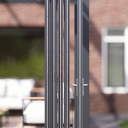 Natis Paweł Stankiewicz - Szklana, składana zabudowa balkonu w Gubinie, z widocznymi detalami konstrukcyjnymi i uchwytami, na tle ceglanego budynku i zieleni.