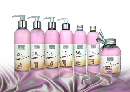 Rząd siedmiu butelek kosmetyków Bingo Silk Pure, od lewej: płyn do mycia twarzy i szyi, mydło do rąk, mydło do stóp, płyn do higieny intymnej, szampon odżywczy, mleczko pod prysznic, regenerujący...