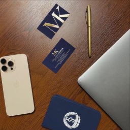 Kancelaria Radcy Prawnego Magdalena Klimek - Biurko z wizytówką radcy prawnego Magdaleny Klimek z Chełma, złotym piórem, telefonem i laptopem. Eleganckie i profesjonalne.