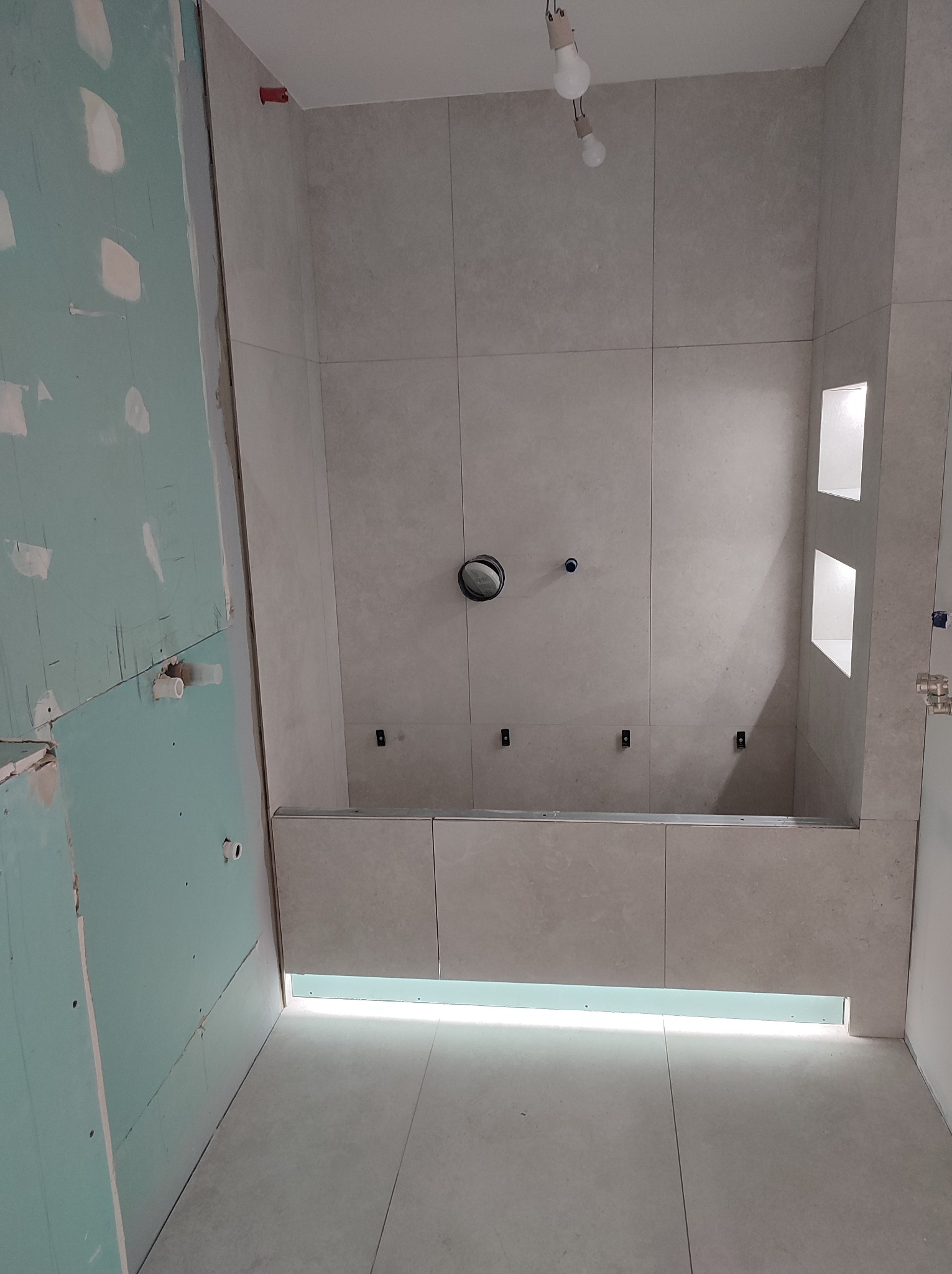 Układanie płytek w łazience w Lubiszewie Tczewskim. Widoczne płytki na ścianach, przygotowane ściany z płyt gipsowych. Etap prac wykończeniowych.