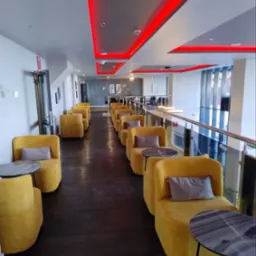 Nowoczesne wnętrze biurowe z ż&oacute;łtymi fotelami i czerwonym oświetleniem LED na suficie. Widok na przestrzeń biurową z przeszkloną balustradą.