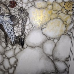 Gaga - Artystyczne malowanie ściany z motywem czarodzieja i elementami dekoracyjnymi w odcieniach bieli, szarości i złota, imitujące pęknięcia i kamienną fakturę.