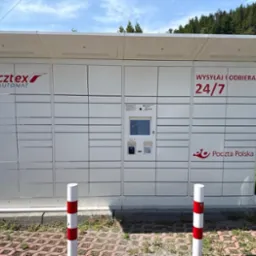 Paczkomat Pocztex Automat z kamerami monitoringu, umieszczony na zewnątrz, z widocznym ekranem dotykowym i logo Poczty Polskiej. Dostępny 24/7.