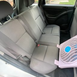 Czyścioch z dojazdem Mobilne sprzatanie - Wnętrze samochodu z szarą tapicerką, widoczne tylne siedzenia i fragment wentylatora, sugerujące proces suszenia po czyszczeniu.