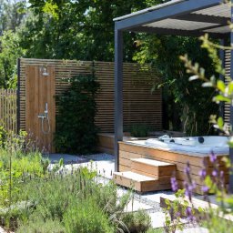 MILA SPÓŁKA Z OGRANICZONĄ ODPOWIEDZIALNOŚCIĄ - Nowoczesny ogród z drewnianą zabudową jacuzzi, prysznicem zewnętrznym i rabatami z lawendą. Minimalistyczny design z elementami naturalnego drewna i zieleni.