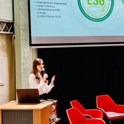 Marta Włodarczyk-Woźniczko Prawnik Przejęcia i finansowania spółek Corporate Governance Compliance Prawo bankowe - Prezentacja ESG: Kobieta z mikrofonem omawia wpływ firm na środowisko, efektywność budynków i odnawialne źródła energii. Na ekranie logo ESG i hasło 'Environment'.