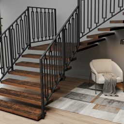 Iron Wood Craft - Nowoczesne schody z drewnianymi stopniami i czarną, metalową balustradą w minimalistycznym wnętrzu. Widoczny fragment salonu z dywanem i fotelem.