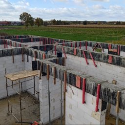 SkyDan - Fundamenty domu z betonu komórkowego, zbrojenie, szalunki, widok z góry na tle krajobrazu wiejskiego. Etap budowy domu.