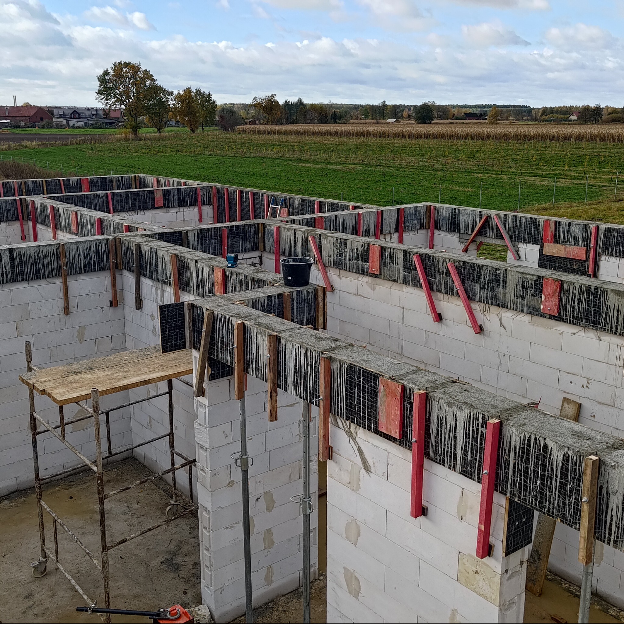 Fundamenty domu z betonu komórkowego, zbrojenie, szalunki, widok z góry na tle krajobrazu wiejskiego. Etap budowy domu.