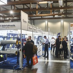 Mateusz Bojdoł - Stoisko targowe firmy Lubas z rurami i hasłem '30+ lat doświadczenia'. W tle widoczni ludzie i inne stoiska. Hala targowa z widoczną konstrukcją dachu.