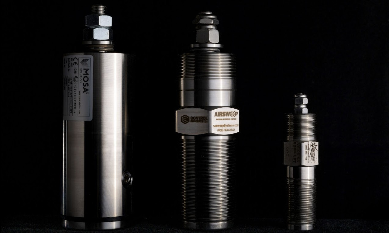 Trzy cylindryczne, metalowe urządzenia o różnej wielkości, ustawione obok siebie na czarnym tle. Widoczne etykiety i gwintowane elementy.