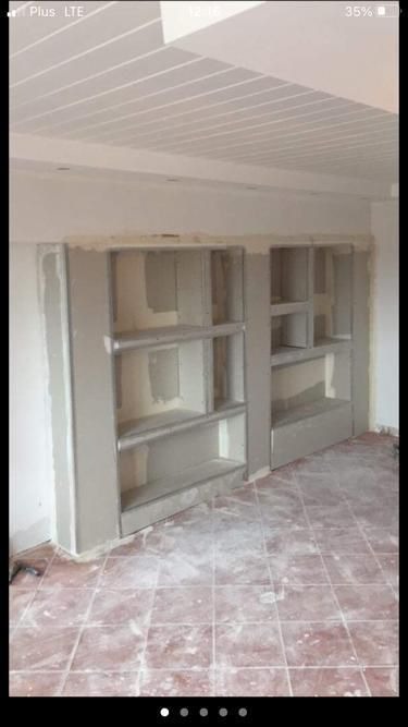 Dwa wnękowe regały z płyt karton-gips na ścianie, w trakcie szpachlowania i wygładzania, widoczne płytki na podłodze, sufit podwieszany.